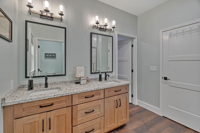 full bath with wood finished floors, double vanity, and baseboards