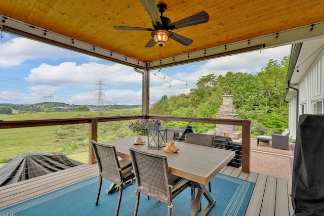 deck featuring a multi sided fireplace, outdoor dining area, and ceiling fan