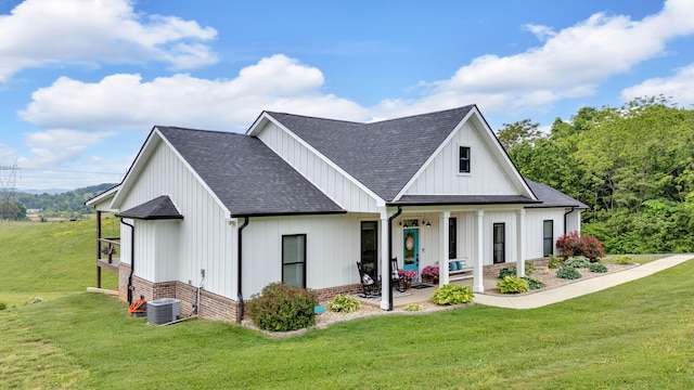 rear view of property featuring a shingled roof, a yard, and covered porch