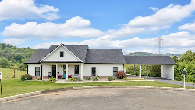 modern farmhouse style home with roof with shingles, a front yard, covered porch, asphalt driveway, and an attached carport