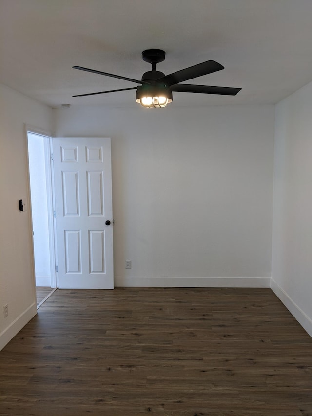 empty room with a ceiling fan, baseboards, and dark wood-type flooring