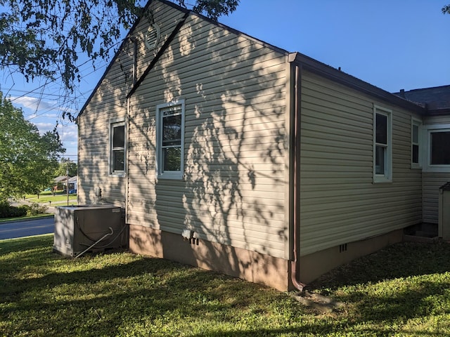view of side of property featuring a yard, central AC, and crawl space