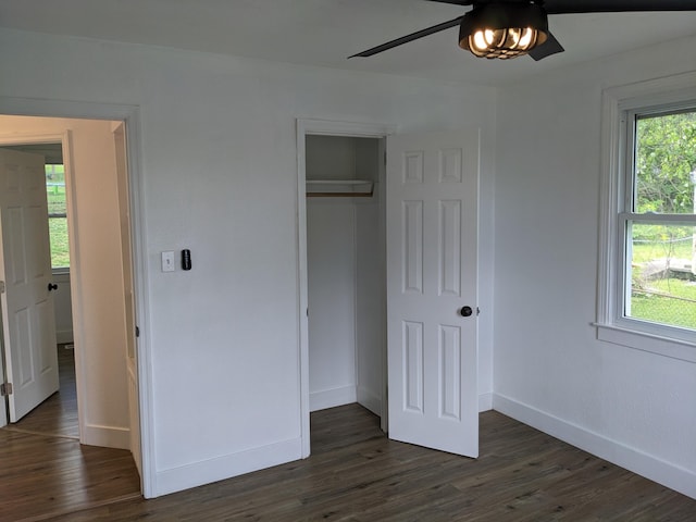 unfurnished bedroom featuring a closet, dark wood finished floors, baseboards, and ceiling fan