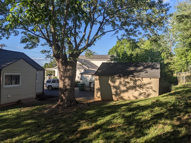 back of house featuring a lawn, an outdoor structure, and a storage unit