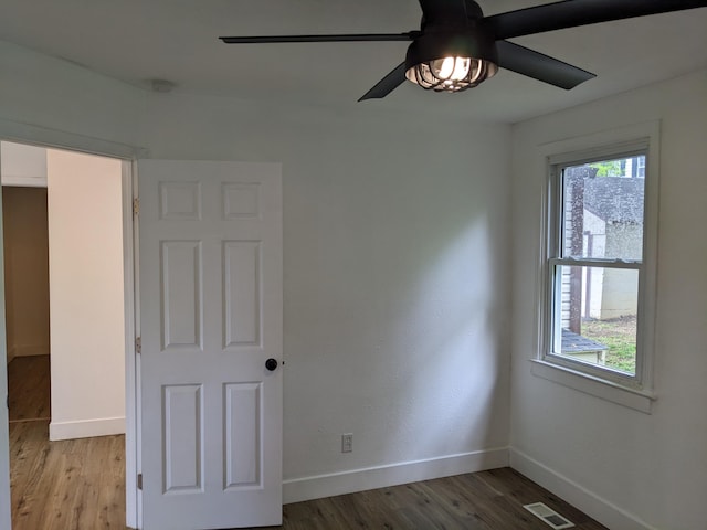 unfurnished room featuring baseboards, visible vents, a ceiling fan, and wood finished floors