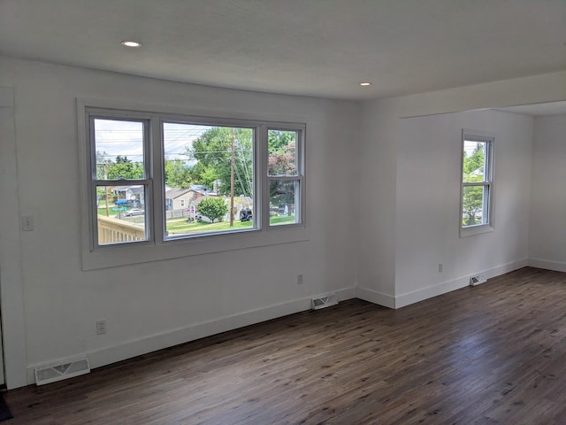 spare room with dark wood-style floors, plenty of natural light, and visible vents