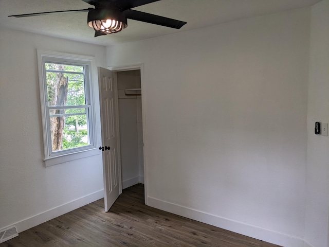 unfurnished bedroom with multiple windows, wood finished floors, visible vents, and baseboards