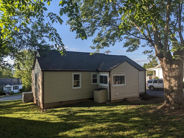 back of house with a shingled roof, a yard, and crawl space