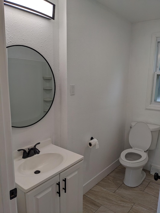half bathroom with toilet, baseboards, and vanity