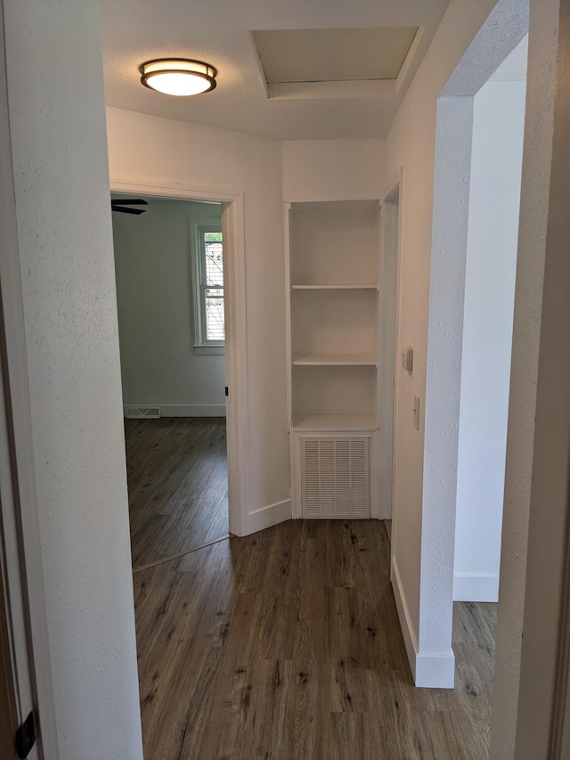 hall featuring wood finished floors, attic access, and baseboards