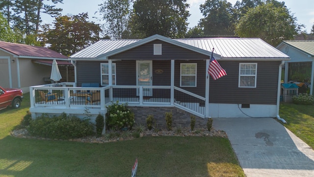 view of front of home with a porch, a front yard, and metal roof