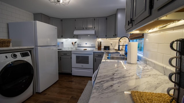 kitchen featuring gray cabinetry, under cabinet range hood, washer / clothes dryer, tasteful backsplash, and white appliances