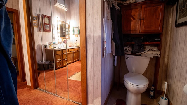 bathroom featuring a wall mounted air conditioner, wood walls, and toilet