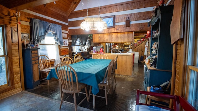 dining space featuring vaulted ceiling with beams, wooden walls, and a chandelier