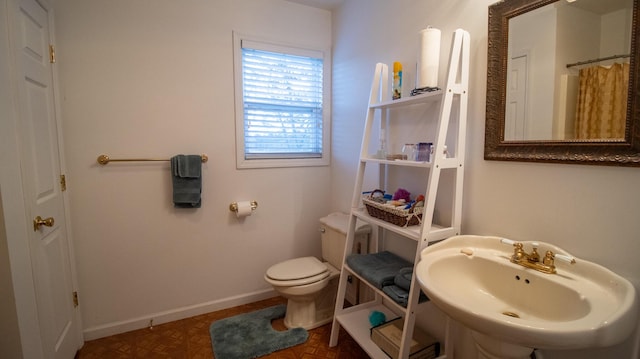 bathroom featuring walk in shower, toilet, sink, and parquet flooring