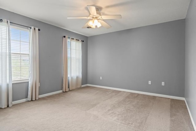 unfurnished room with ceiling fan, light colored carpet, and baseboards