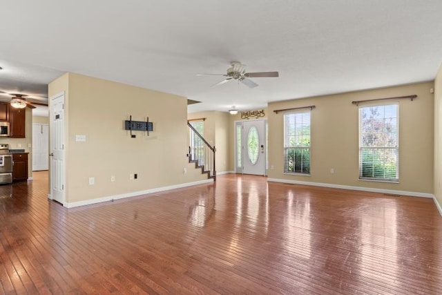 unfurnished living room featuring stairway, ceiling fan, dark wood-style flooring, and baseboards