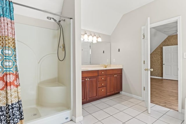 full bathroom with a shower with curtain, tile patterned floors, baseboards, vaulted ceiling, and vanity