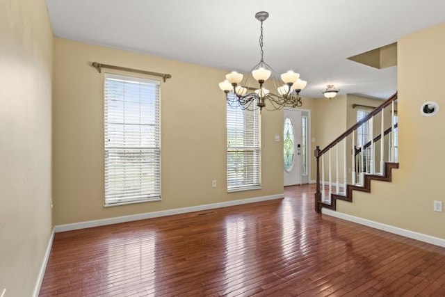 foyer with stairway, a chandelier, wood-type flooring, and plenty of natural light
