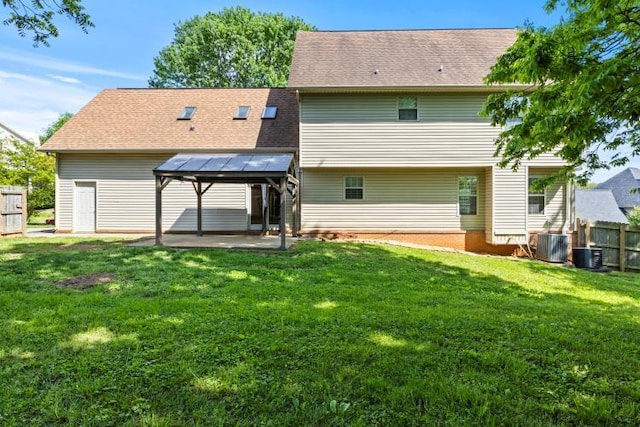 rear view of house with central air condition unit, a patio area, fence, and a yard