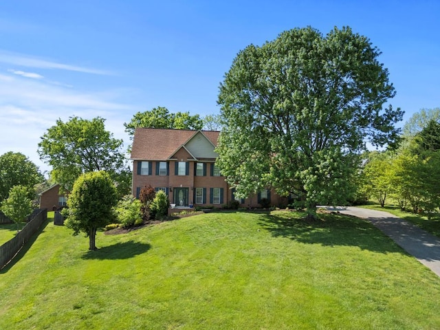 colonial-style house featuring a front lawn and fence