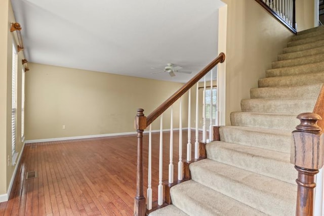 staircase featuring a ceiling fan, baseboards, visible vents, and wood-type flooring