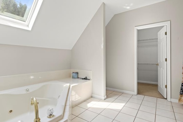 bathroom with tile patterned flooring, a whirlpool tub, baseboards, and vaulted ceiling with skylight