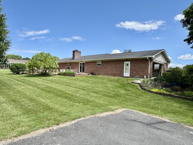 rear view of house with brick siding, a yard, and a chimney