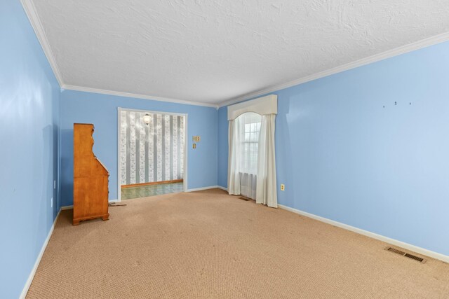 empty room featuring visible vents, ornamental molding, baseboards, a textured ceiling, and carpet