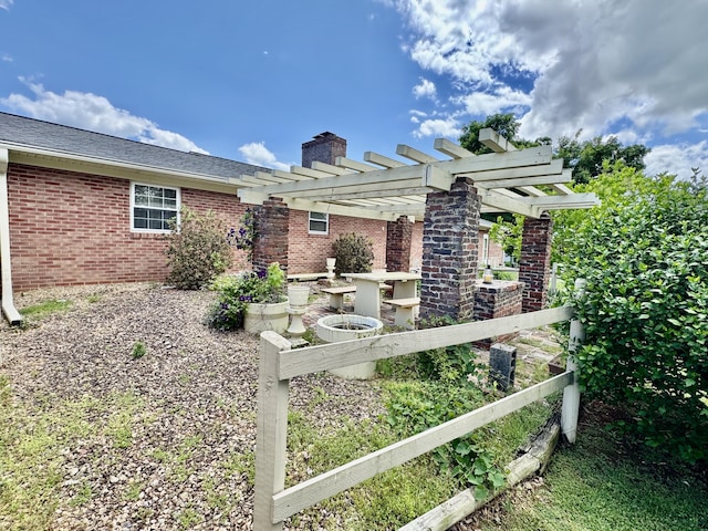 exterior space featuring brick siding, a pergola, and a chimney