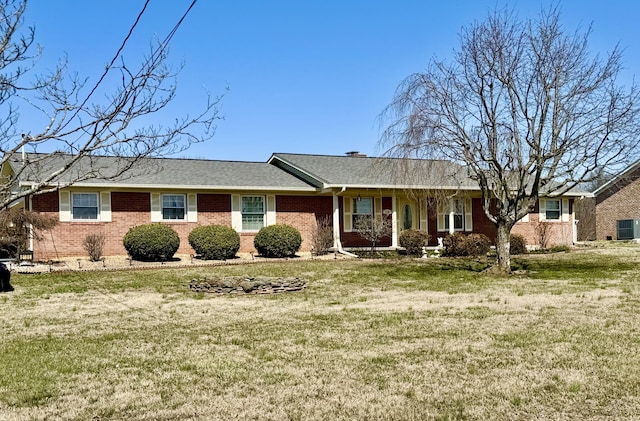 single story home featuring brick siding, cooling unit, and a front yard