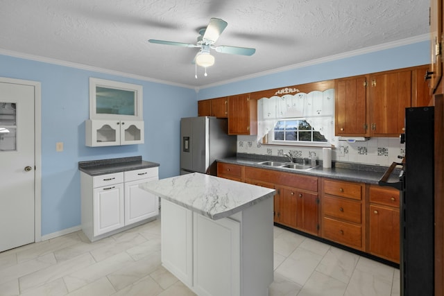 kitchen with a ceiling fan, marble finish floor, stainless steel fridge, brown cabinets, and a sink