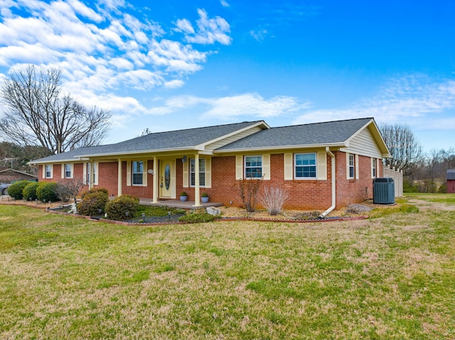 ranch-style house with a shingled roof, a front lawn, brick siding, a porch, and central AC unit