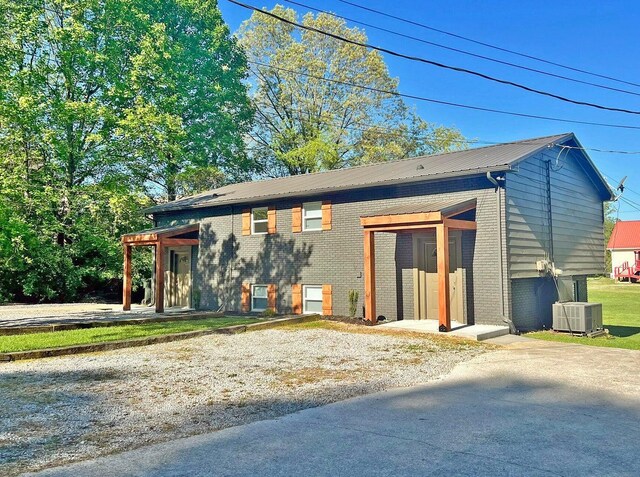 view of front of house with brick siding, cooling unit, and metal roof