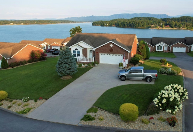 view of front of property with a garage, a front lawn, and a water and mountain view