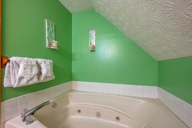 bathroom featuring vaulted ceiling, a tub, and a textured ceiling