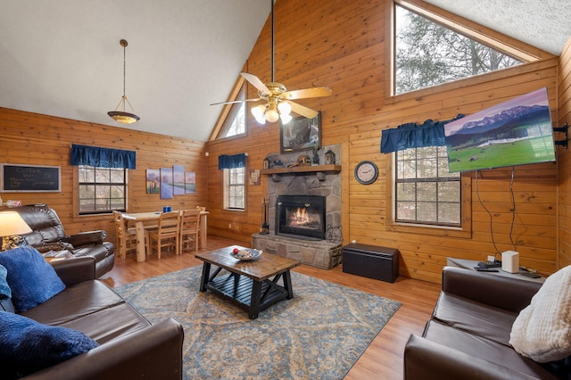living room with a healthy amount of sunlight, a stone fireplace, and light wood-type flooring