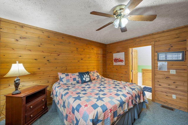 bedroom featuring ceiling fan, wooden walls, carpet floors, and a textured ceiling