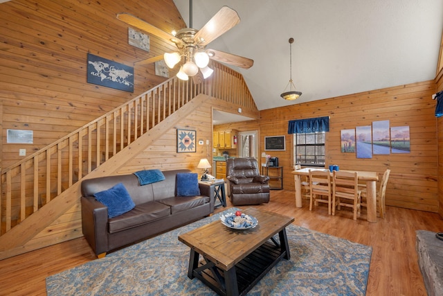 living room featuring hardwood / wood-style floors, high vaulted ceiling, ceiling fan, and wood walls