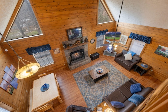 living room with hardwood / wood-style floors, a fireplace, high vaulted ceiling, and wood walls