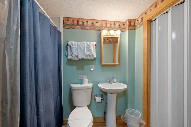 bathroom featuring walk in shower, sink, a textured ceiling, and toilet