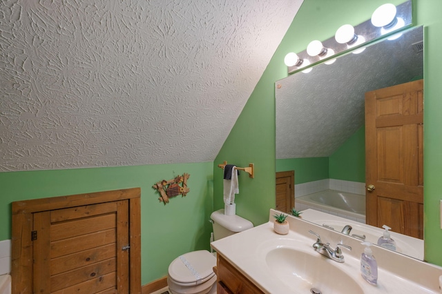 bathroom with lofted ceiling, vanity, a textured ceiling, a tub, and toilet