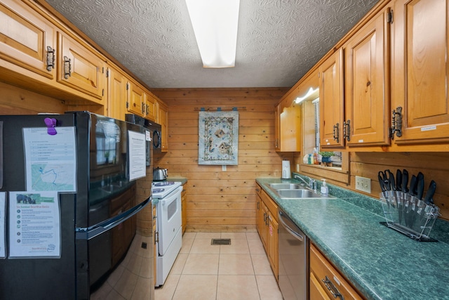 kitchen featuring wooden walls, sink, light tile patterned floors, black appliances, and a textured ceiling