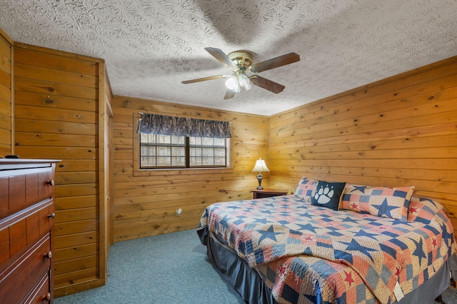 carpeted bedroom with ceiling fan, wooden walls, and a textured ceiling