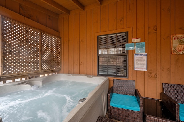 misc room with beamed ceiling, a jacuzzi, and wood walls