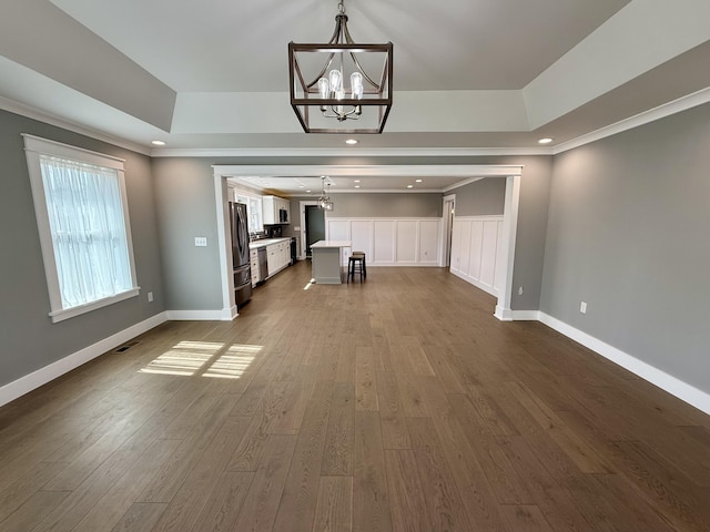 interior space featuring visible vents, a chandelier, a raised ceiling, and dark wood-style flooring