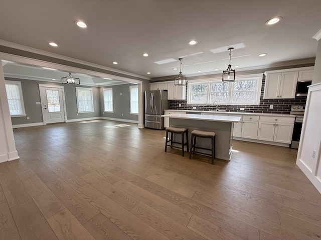 kitchen with a center island, crown molding, appliances with stainless steel finishes, open floor plan, and wood finished floors