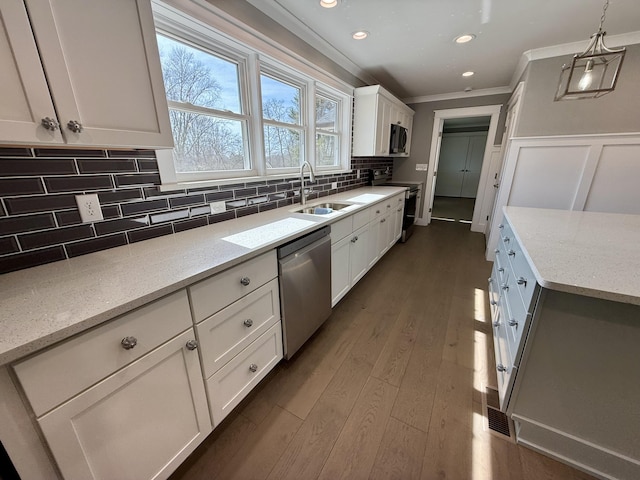 kitchen with stainless steel appliances, dark wood-style flooring, a sink, white cabinetry, and ornamental molding