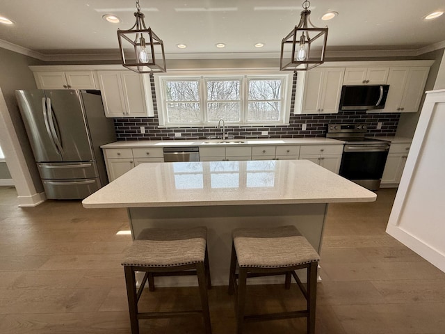 kitchen featuring stainless steel appliances, a sink, decorative backsplash, and ornamental molding