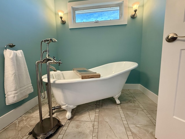 full bath with marble finish floor, baseboards, and a freestanding bath